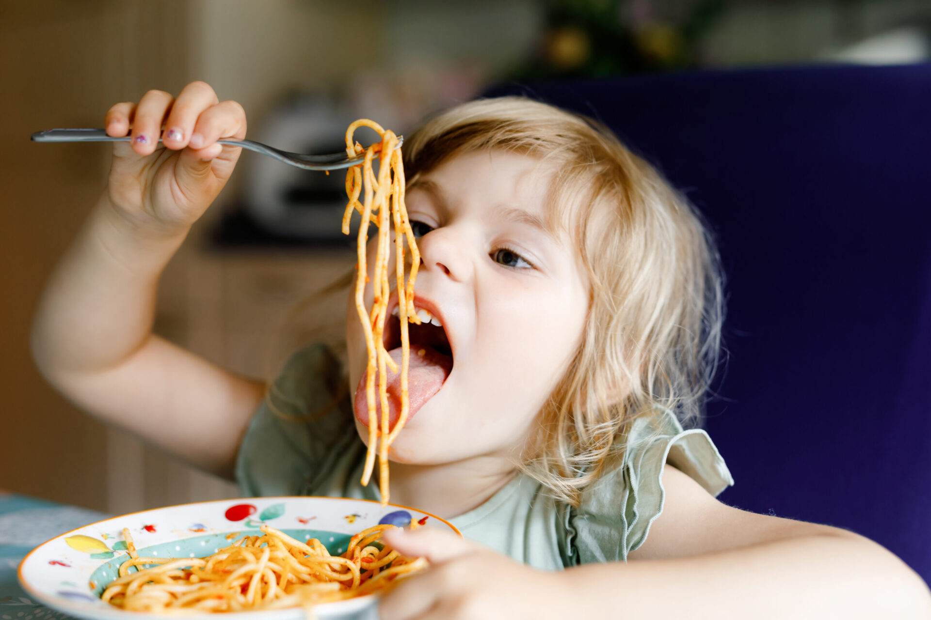 Kleinkind isst Spaghetti mit Tomatensoße.